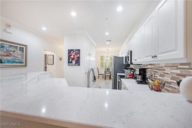 kitchen featuring light stone countertops, kitchen peninsula, crown molding, white cabinets, and appliances with stainless steel finishes