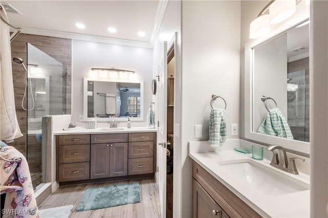 bathroom featuring wood-type flooring, vanity, a shower with door, and ornamental molding