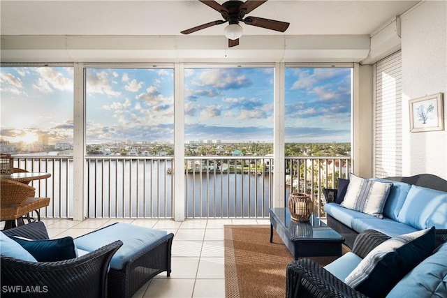 sunroom / solarium with ceiling fan and a water view