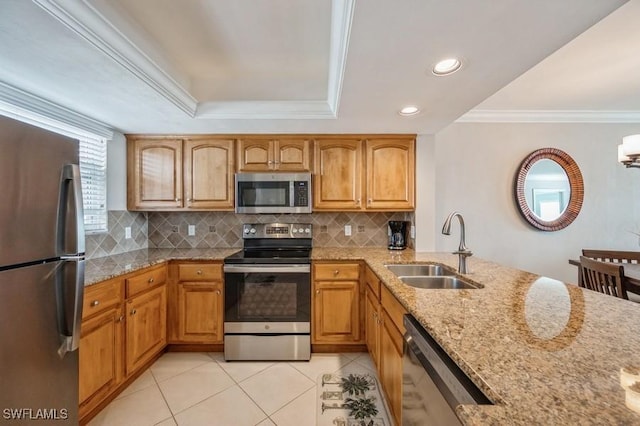 kitchen featuring light stone countertops, decorative backsplash, crown molding, appliances with stainless steel finishes, and sink