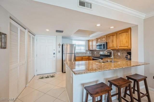 kitchen featuring stainless steel appliances, sink, kitchen peninsula, decorative backsplash, and light stone countertops