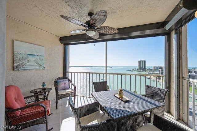 sunroom featuring ceiling fan and a water view