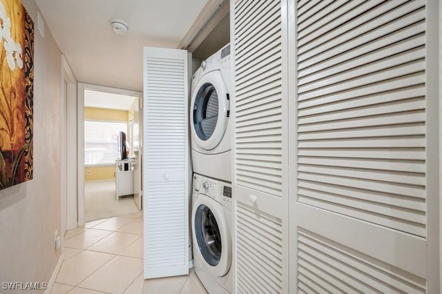 clothes washing area featuring light tile patterned floors and stacked washer / drying machine