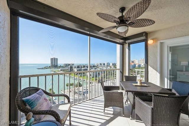 sunroom / solarium featuring ceiling fan and a water view