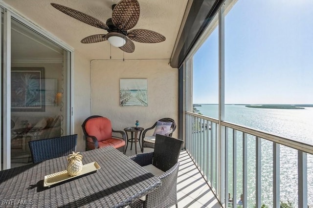 sunroom / solarium with plenty of natural light, ceiling fan, and a water view