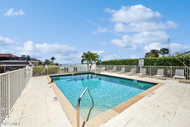 view of swimming pool featuring a patio area and a water view