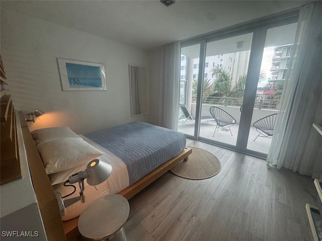 bedroom with access to outside, a wall of windows, and hardwood / wood-style flooring