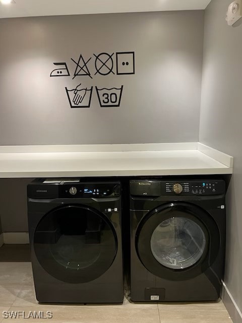 laundry area featuring washing machine and clothes dryer and light tile patterned floors