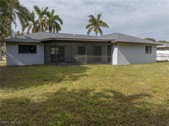 rear view of house featuring a sunroom and a lawn