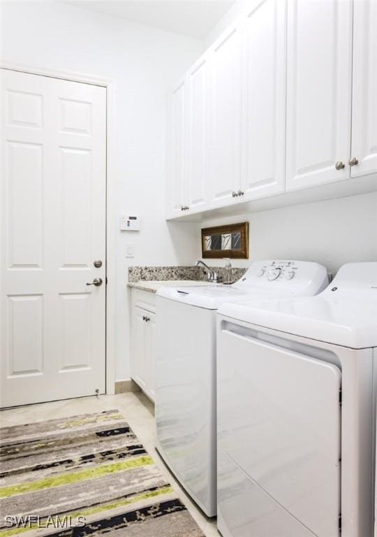 clothes washing area featuring cabinets and separate washer and dryer