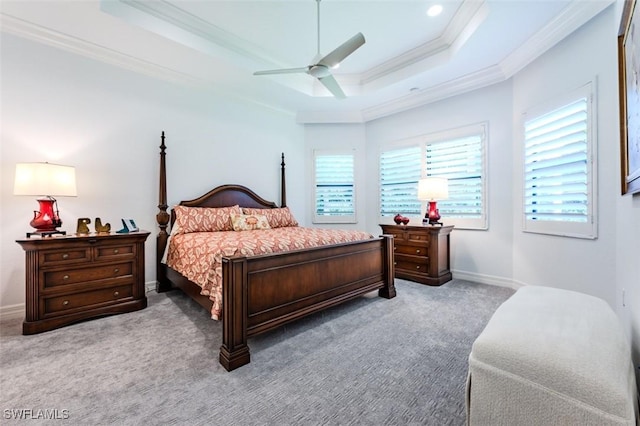 carpeted bedroom with a raised ceiling, multiple windows, ceiling fan, and crown molding