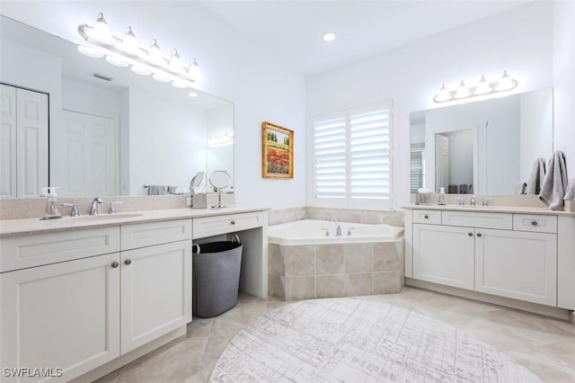 bathroom with tile patterned floors, vanity, and a relaxing tiled tub