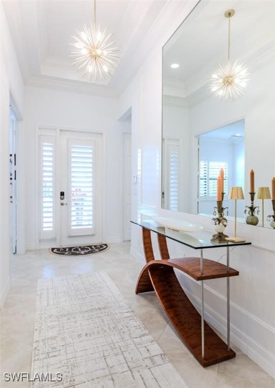 tiled entrance foyer featuring a raised ceiling, crown molding, a towering ceiling, and a chandelier