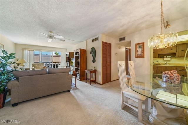 living room with a textured ceiling, light carpet, and ceiling fan with notable chandelier