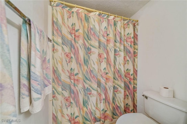 bathroom featuring walk in shower, a textured ceiling, and toilet