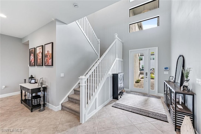 entryway with a towering ceiling and light tile patterned flooring