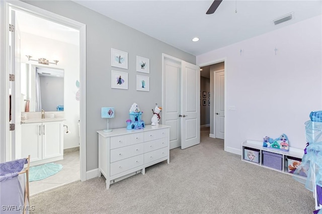 carpeted bedroom featuring ensuite bath, ceiling fan, and sink