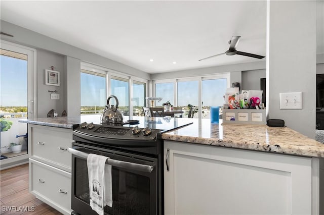 kitchen featuring range with electric cooktop, light stone countertops, white cabinets, and light hardwood / wood-style floors