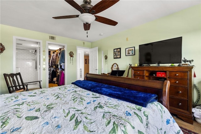 bedroom with hardwood / wood-style flooring, a walk in closet, ceiling fan, ensuite bath, and a closet