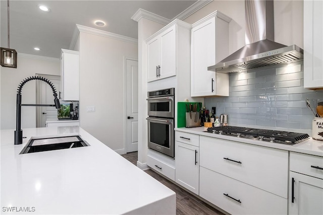 kitchen featuring white cabinets, sink, hanging light fixtures, wall chimney exhaust hood, and stainless steel appliances