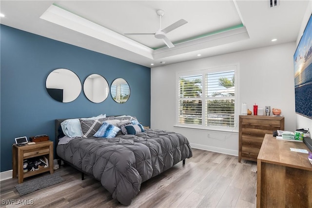 bedroom featuring wood-type flooring, a raised ceiling, and ceiling fan