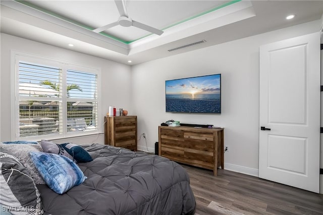 bedroom featuring ceiling fan, dark hardwood / wood-style flooring, and a raised ceiling