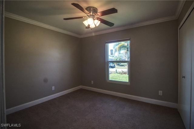 empty room featuring ceiling fan, dark colored carpet, ornamental molding, and baseboards