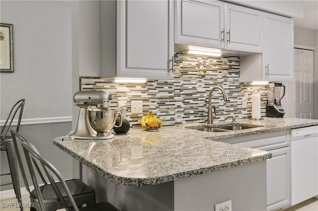 kitchen with white cabinets, decorative backsplash, dishwasher, and sink