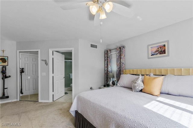 bedroom with ceiling fan, light colored carpet, and ensuite bath