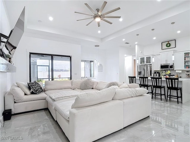 living room with a raised ceiling and ceiling fan