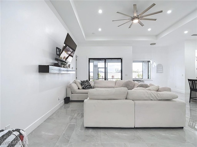 living room with a tray ceiling and ceiling fan