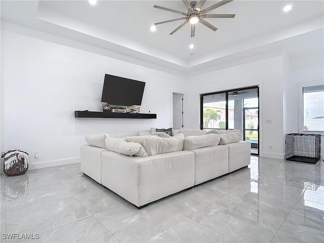 living room featuring ceiling fan and a raised ceiling