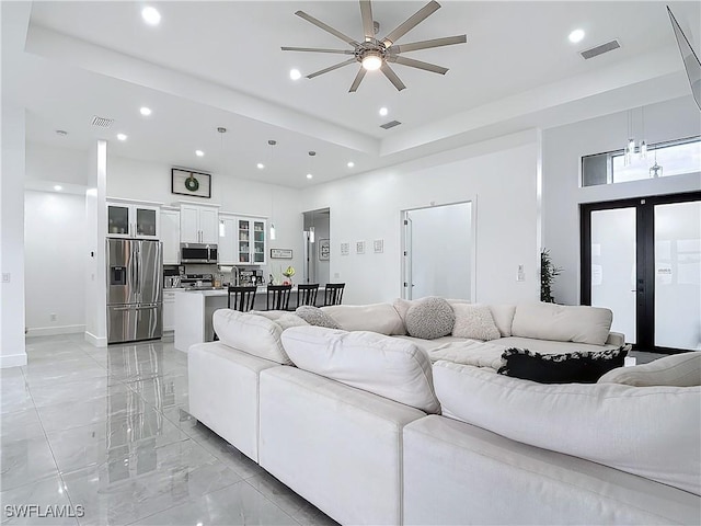 living room featuring a raised ceiling, ceiling fan, french doors, and a high ceiling