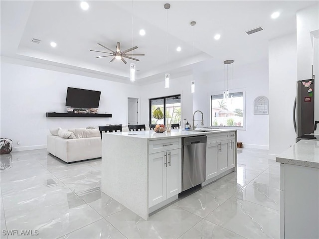 kitchen with pendant lighting, a kitchen island with sink, white cabinets, a raised ceiling, and appliances with stainless steel finishes