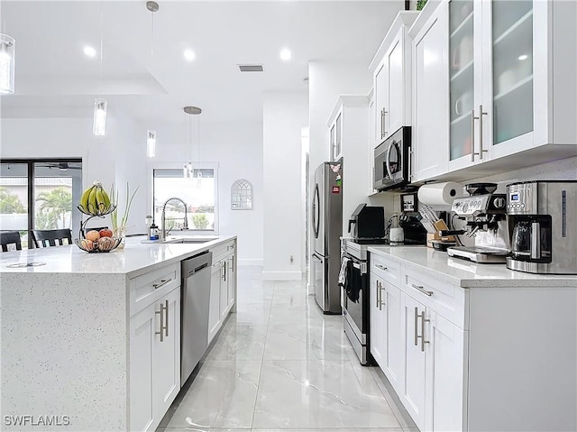 kitchen featuring sink, hanging light fixtures, a healthy amount of sunlight, white cabinetry, and stainless steel appliances