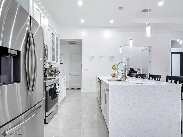 kitchen with pendant lighting, white cabinetry, sink, and appliances with stainless steel finishes