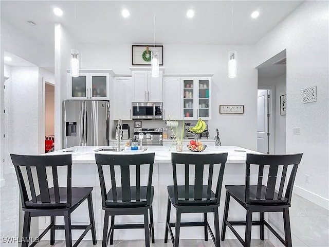 kitchen featuring sink, a kitchen breakfast bar, decorative light fixtures, white cabinets, and appliances with stainless steel finishes