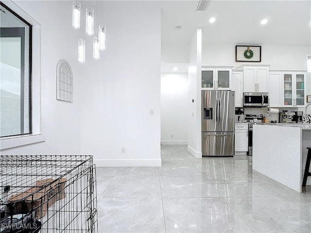 kitchen featuring white cabinets, stainless steel appliances, and decorative light fixtures