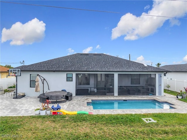 back of house featuring a sunroom, a patio, a jacuzzi, and a lawn