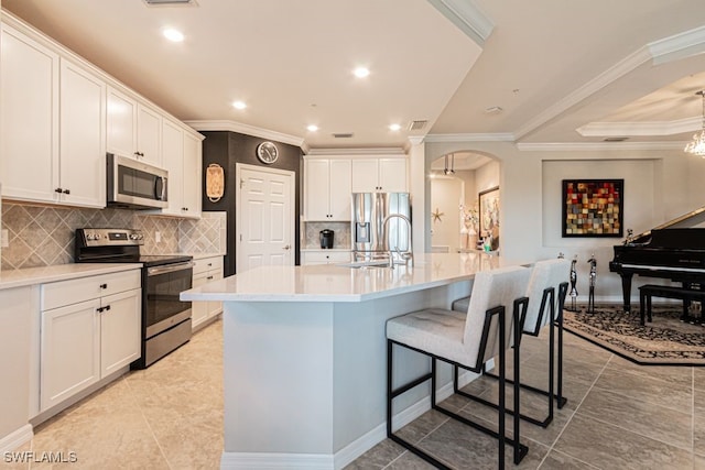 kitchen with backsplash, sink, an island with sink, appliances with stainless steel finishes, and white cabinetry