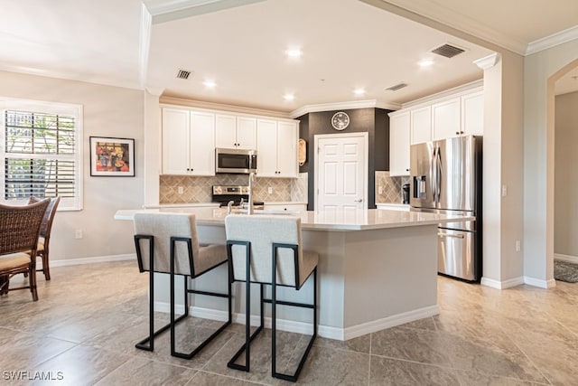 kitchen featuring a kitchen island with sink, white cabinets, stainless steel appliances, and ornamental molding