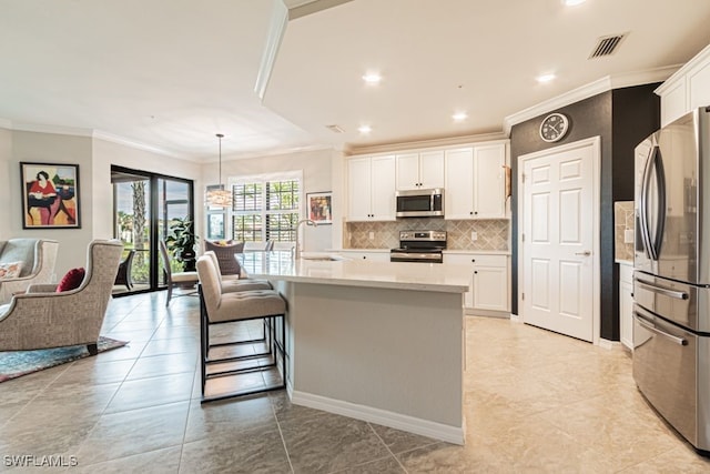 kitchen with pendant lighting, white cabinets, a kitchen island with sink, and appliances with stainless steel finishes