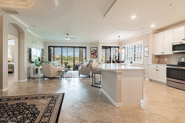 kitchen with appliances with stainless steel finishes, ceiling fan, a center island with sink, decorative light fixtures, and white cabinets