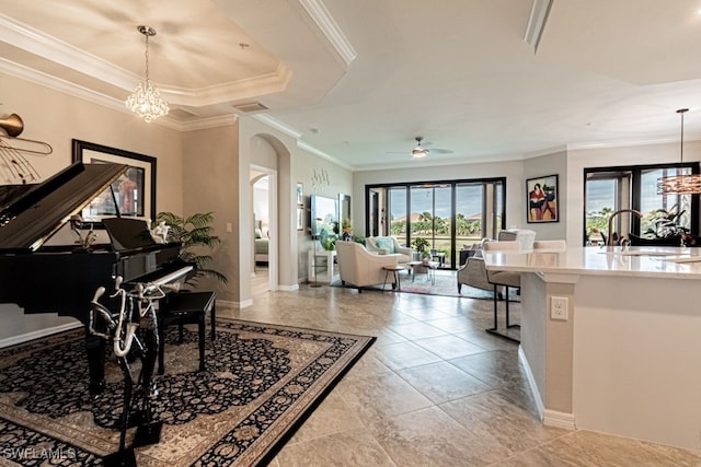 interior space featuring a raised ceiling, crown molding, sink, and ceiling fan with notable chandelier