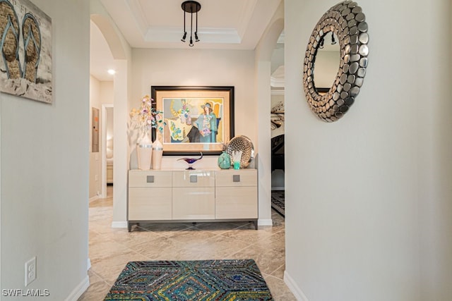 corridor featuring a tray ceiling and ornamental molding