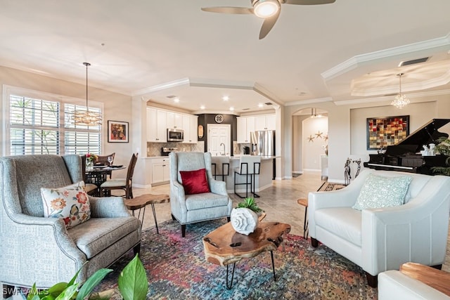 living room featuring crown molding and ceiling fan with notable chandelier