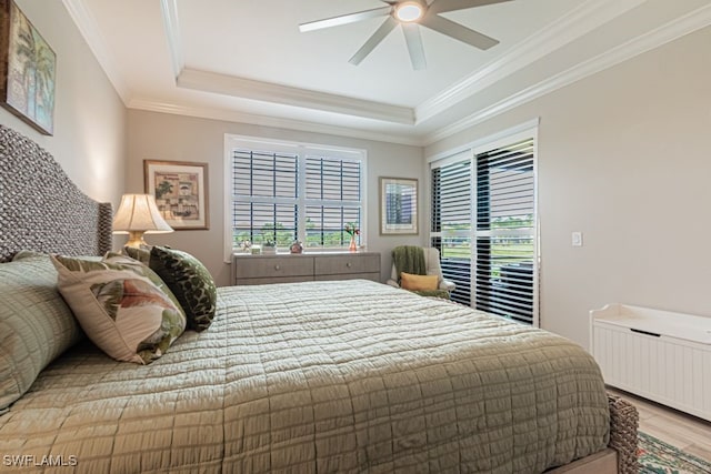 bedroom featuring radiator, hardwood / wood-style flooring, ceiling fan, ornamental molding, and a tray ceiling