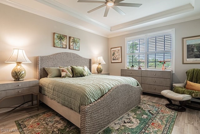 bedroom featuring wood-type flooring, a raised ceiling, ceiling fan, and crown molding