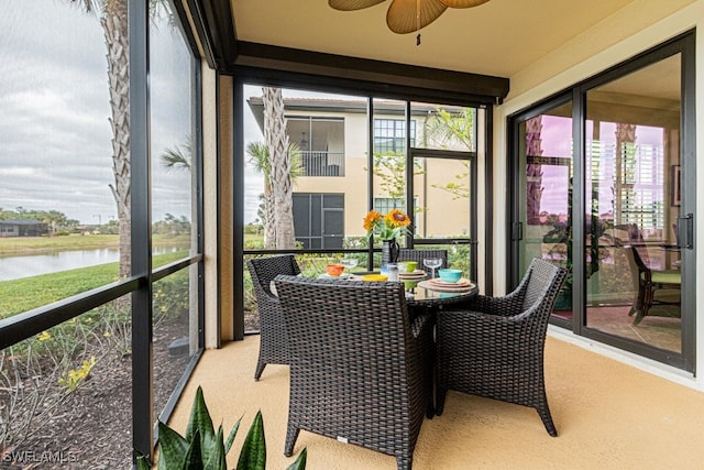 sunroom with ceiling fan and a water view