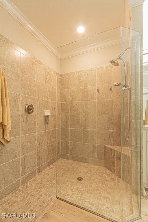 bathroom with a tile shower, hardwood / wood-style flooring, and ornamental molding